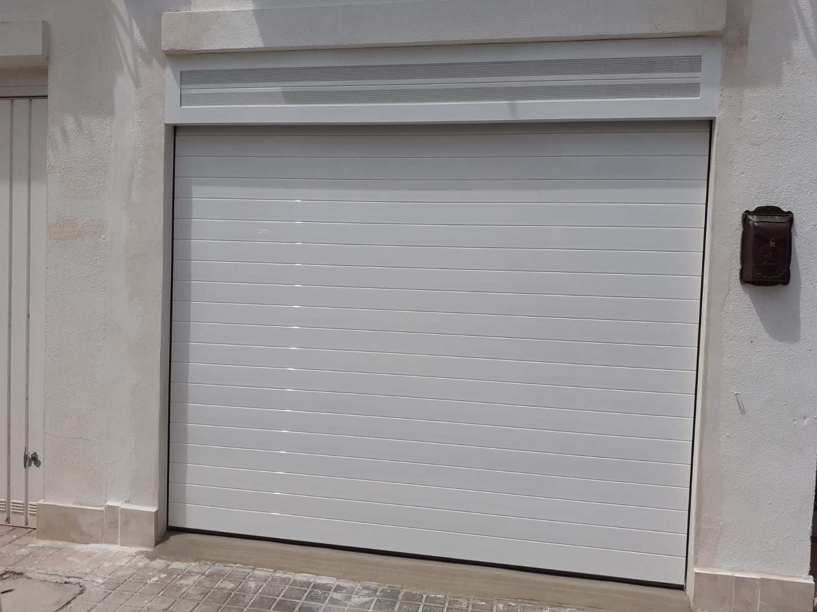 Una puerta de garaje blanca está situada al costado de un edificio.