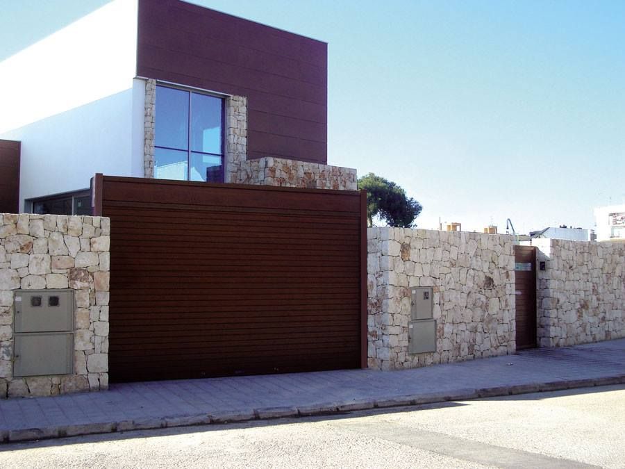 Una casa con un muro de piedra y una puerta de garaje marrón.