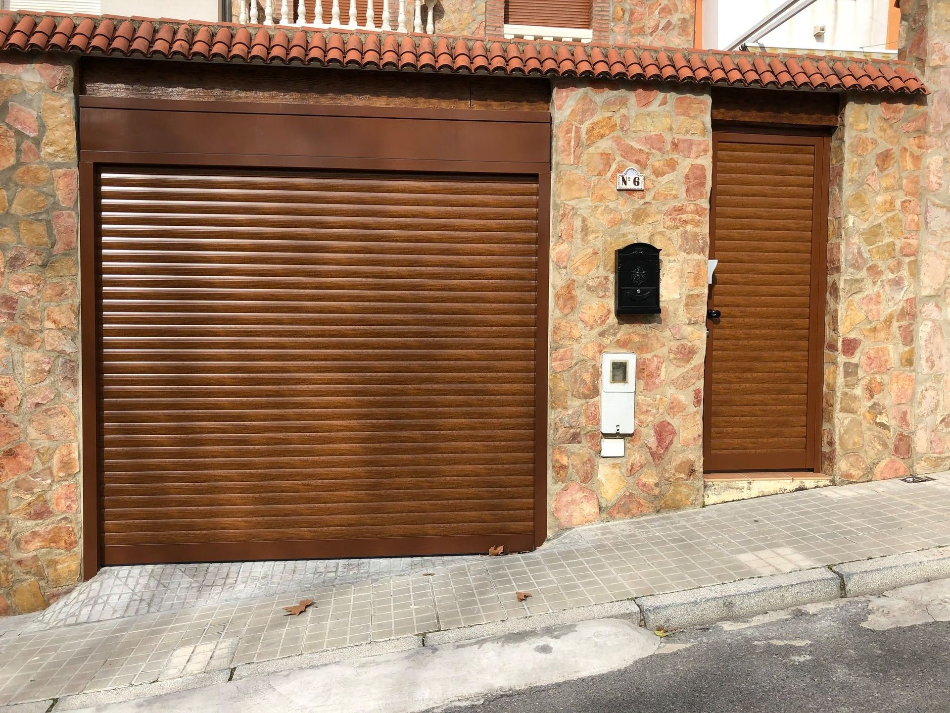 Una puerta de garaje de madera está delante de un edificio de piedra.