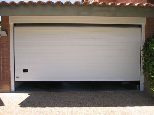 Una puerta de garaje blanca está abierta frente a un edificio de ladrillo.