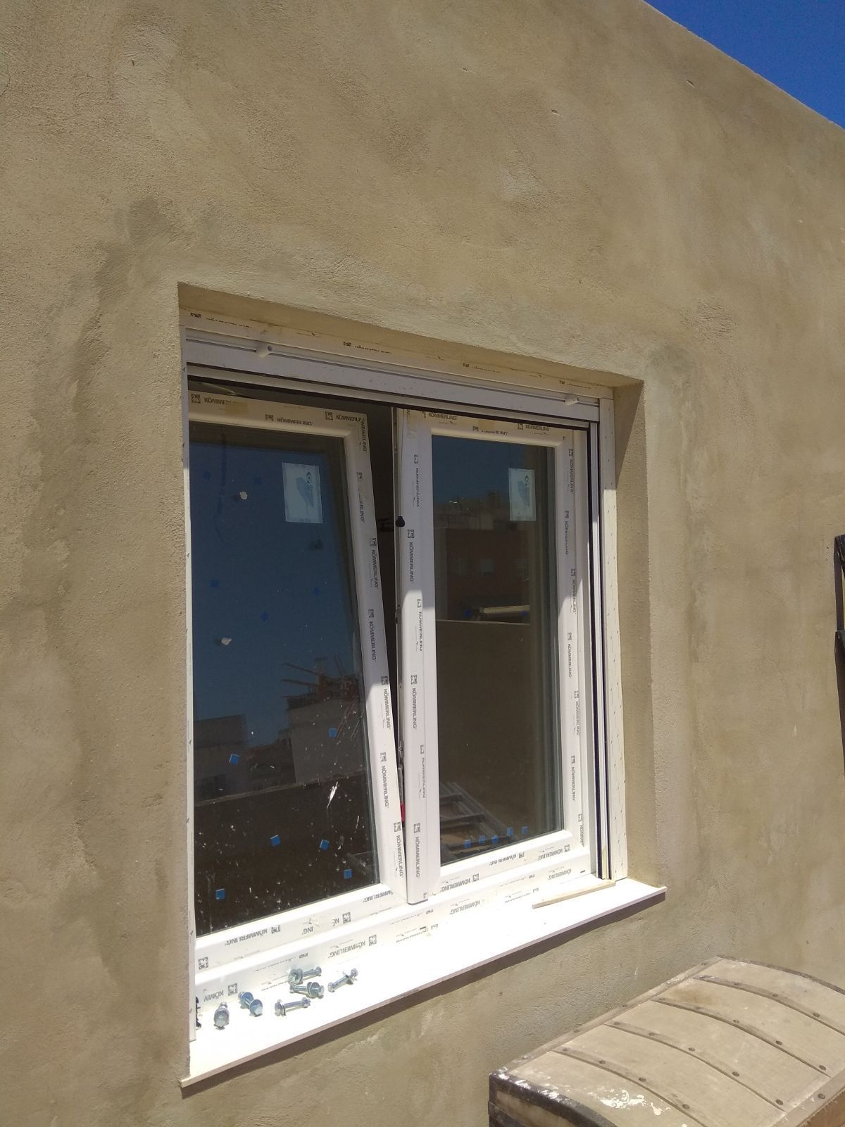 Una ventana en el costado de un edificio con un cielo azul al fondo.