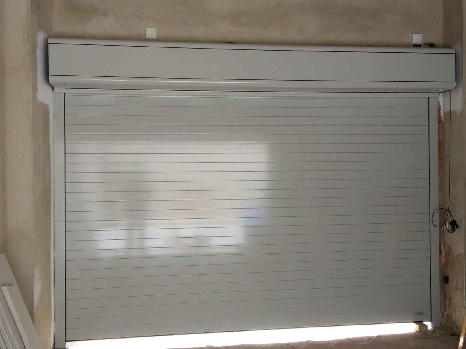 Una puerta de garaje blanca está abierta en una habitación.