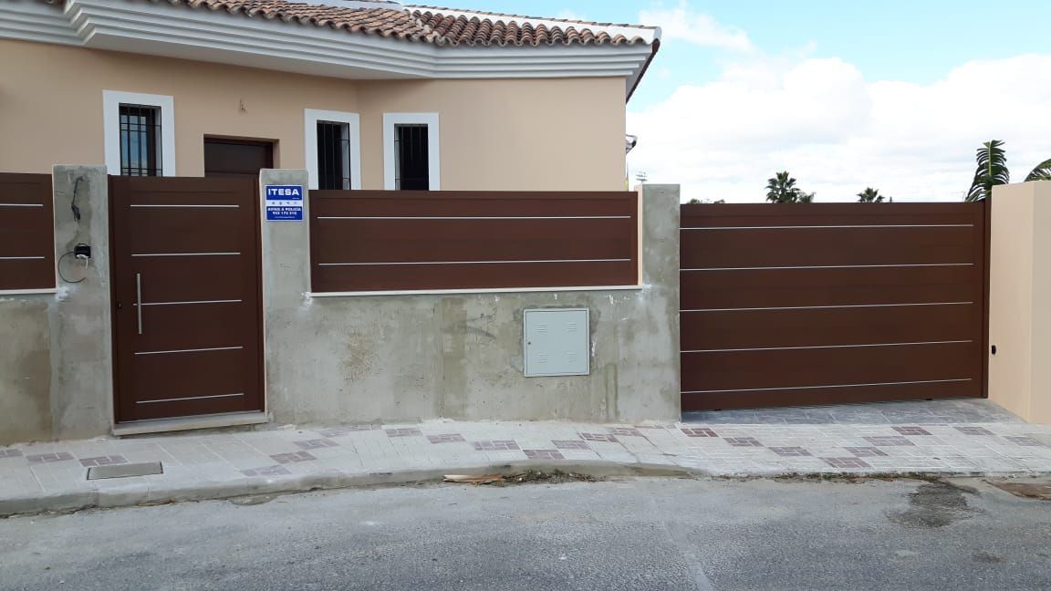 Una casa con una valla marrón y una puerta marrón