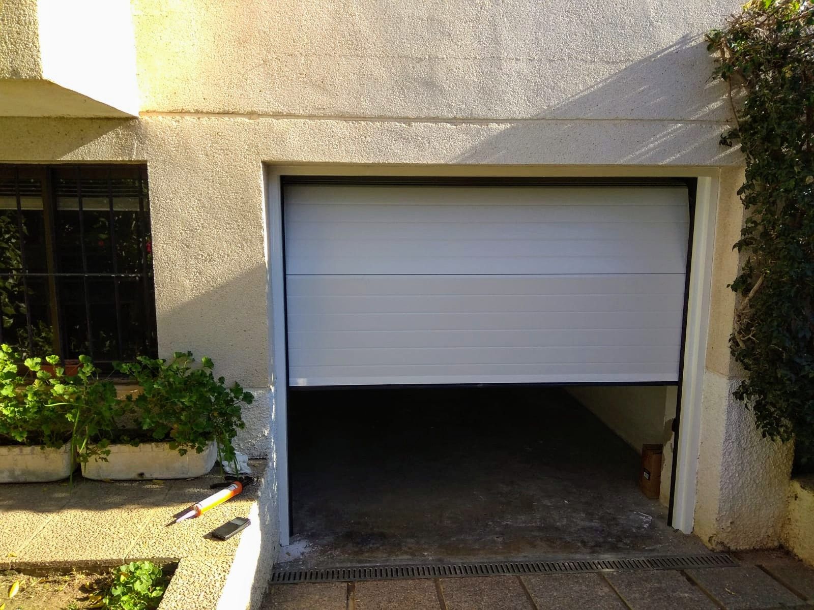 Una puerta de garaje blanca está abierta frente a una casa.