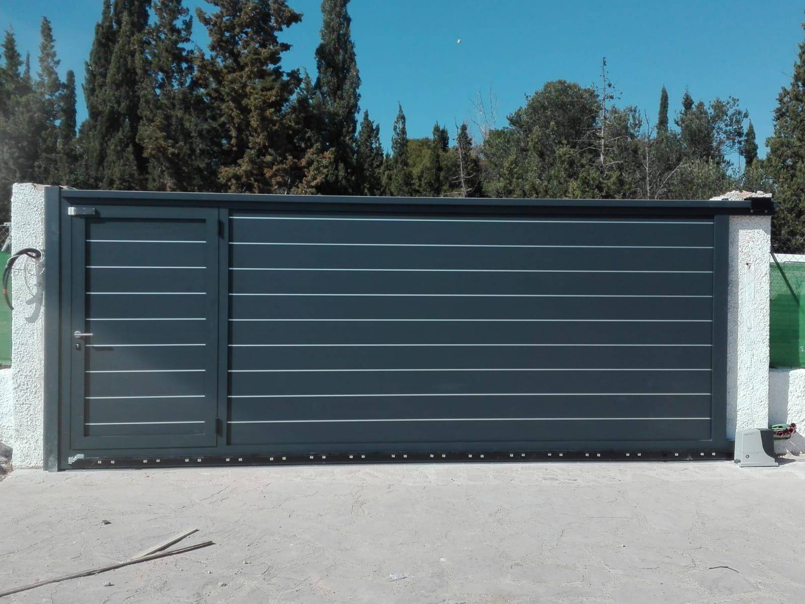 Una puerta corrediza negra con árboles al fondo.