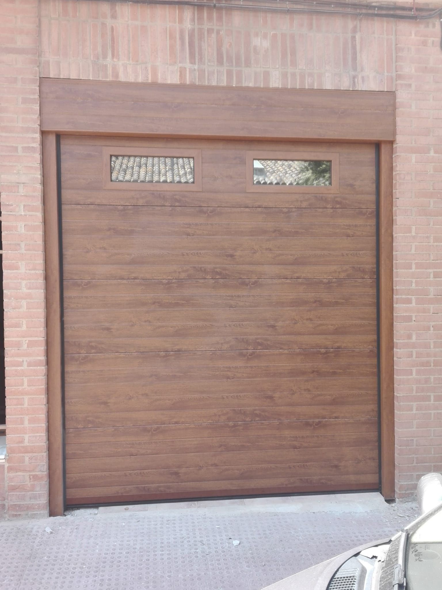 Un coche está aparcado delante de una puerta de garaje de madera.