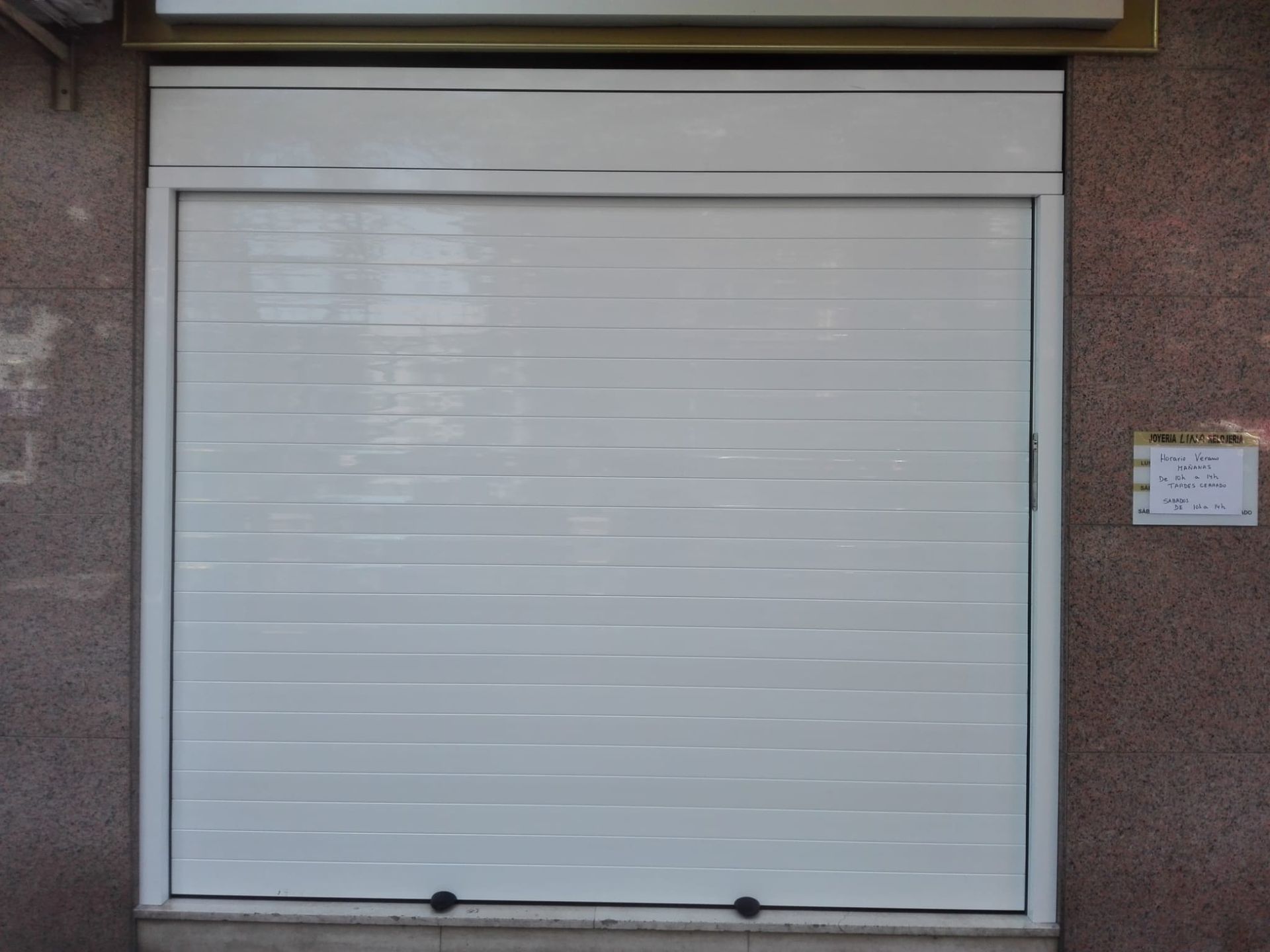 Una puerta de garaje blanca está situada al costado de un edificio.