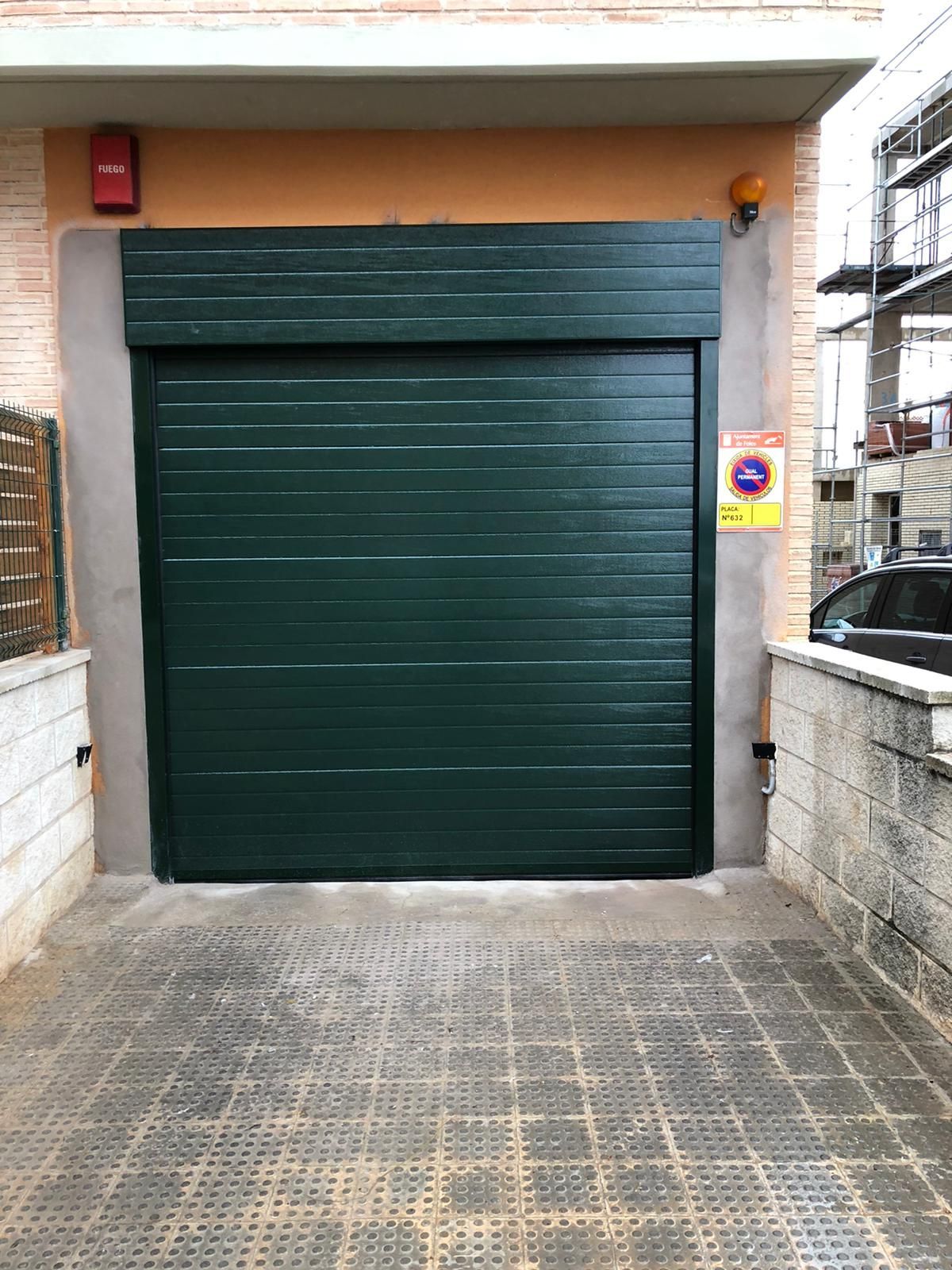 Una puerta de garaje verde está abierta en un estacionamiento.