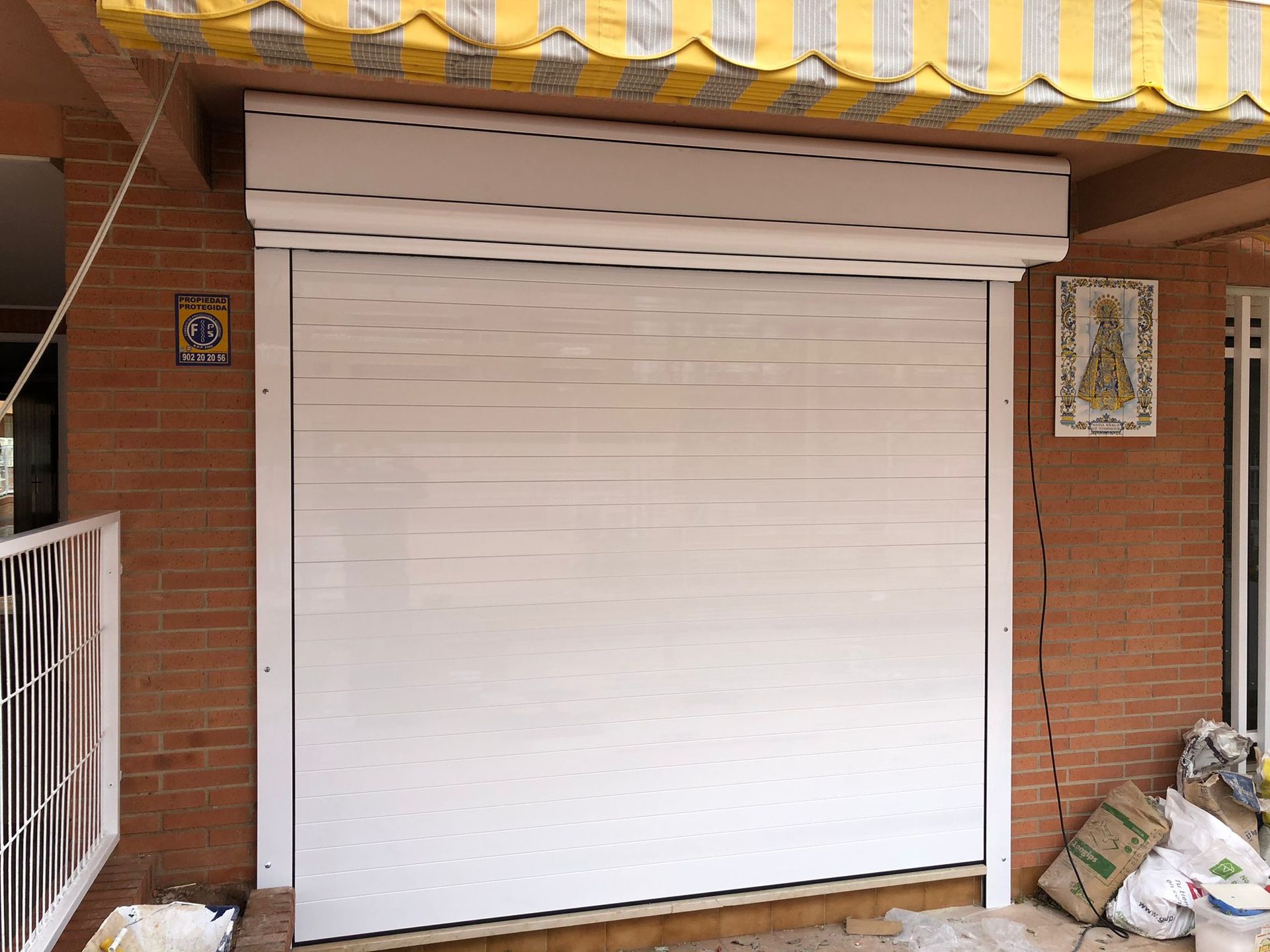 Una puerta de garaje blanca con un toldo amarillo y blanco encima.