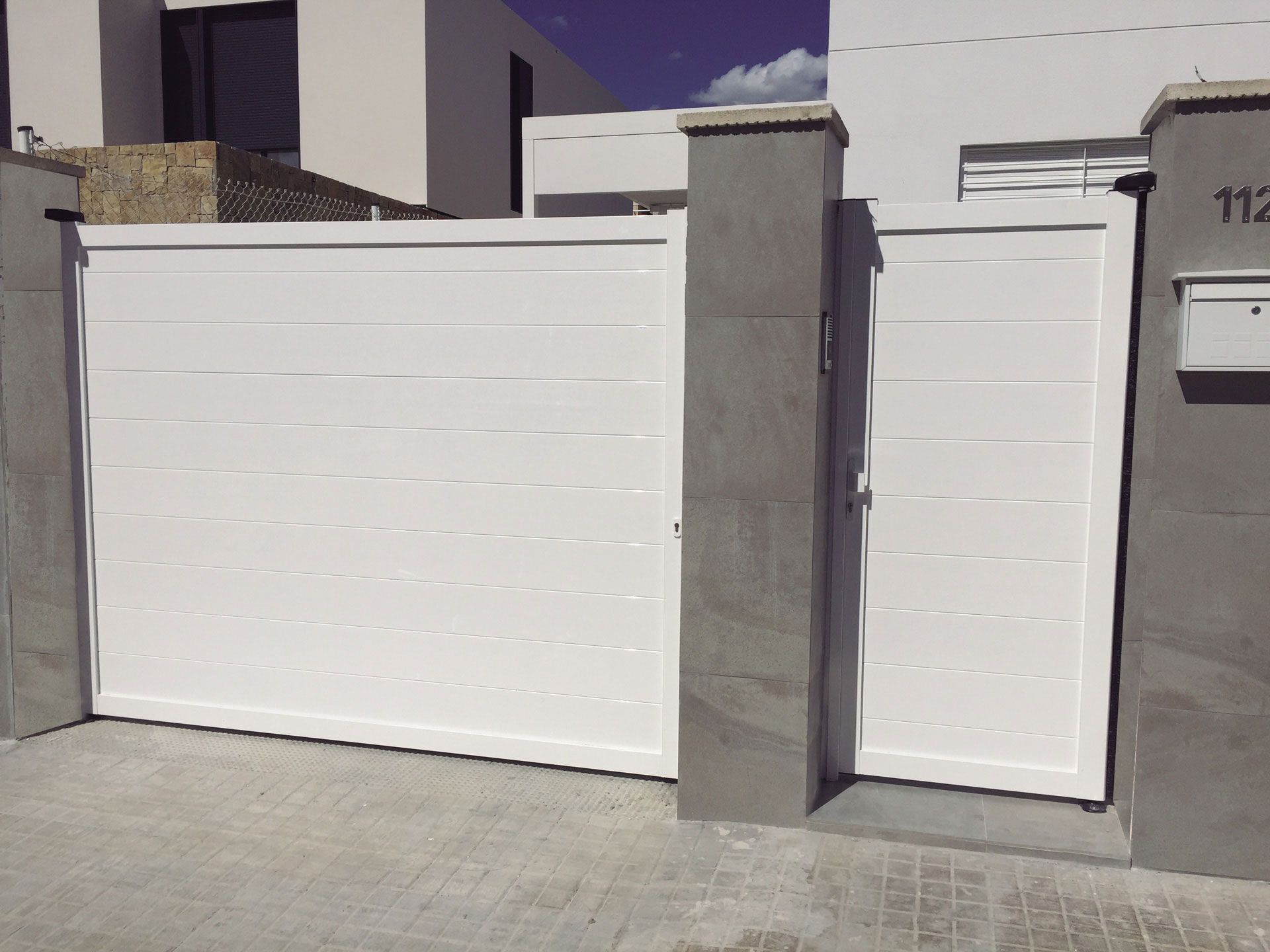 Una puerta corrediza blanca con un buzón delante.