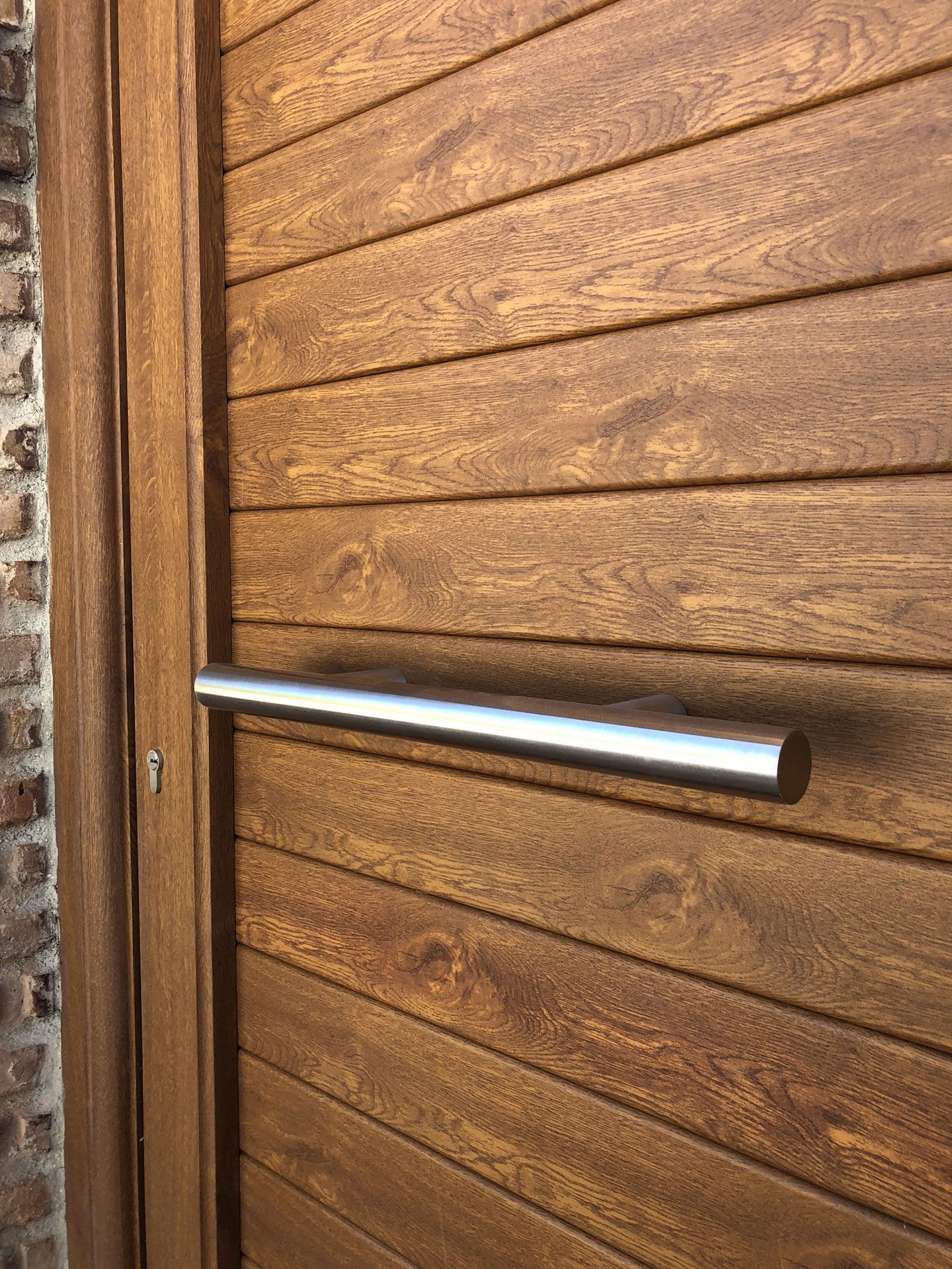 Un primer plano de una puerta de madera con manija de acero inoxidable.