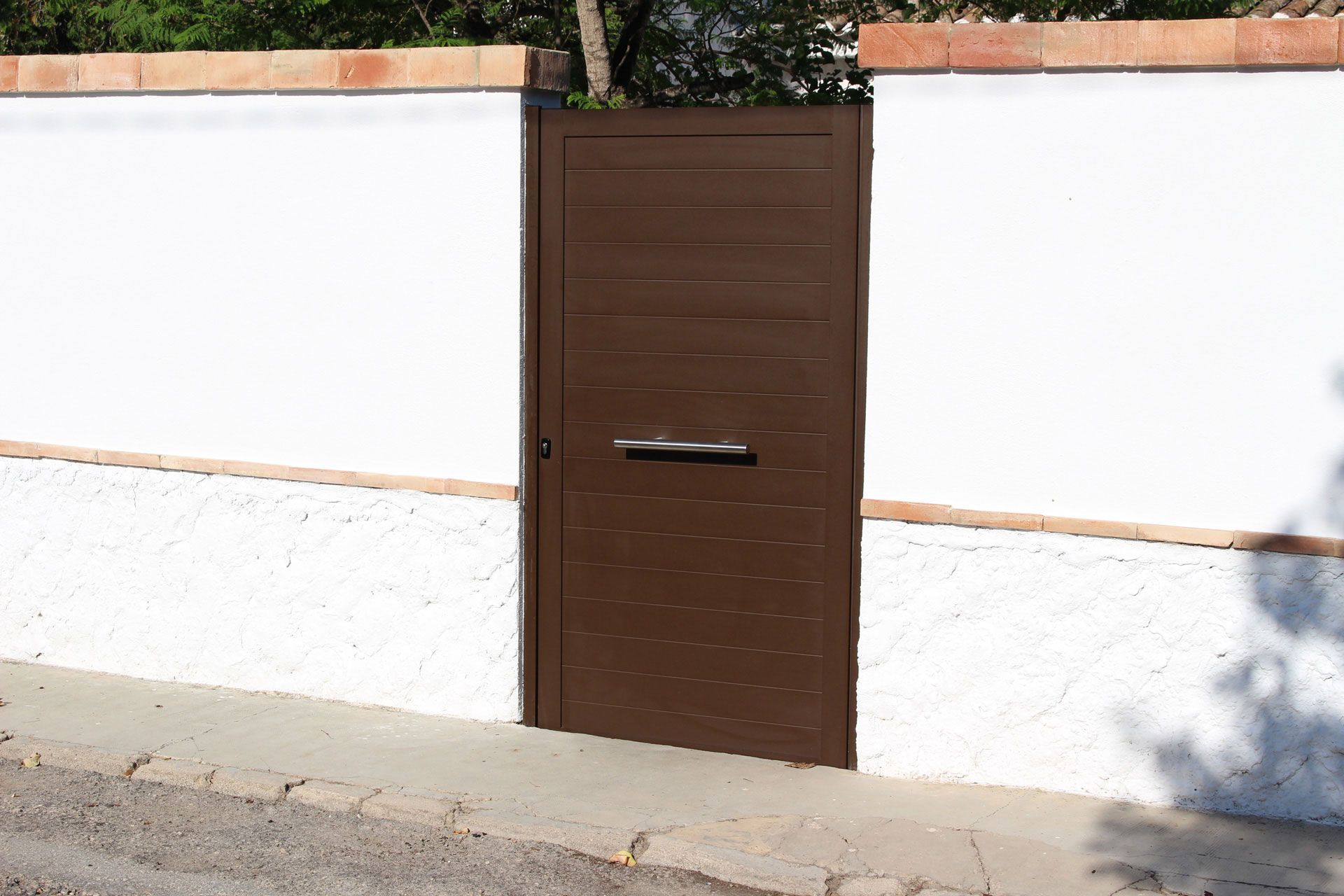 Una puerta marrón está delante de una pared blanca.