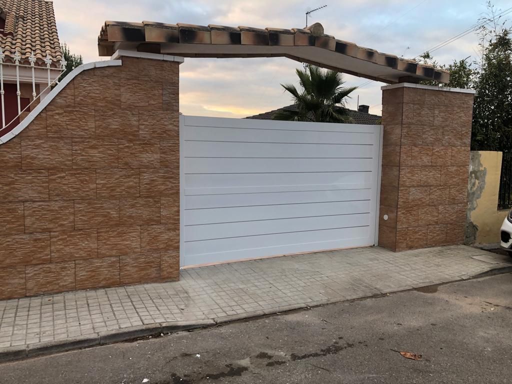 Un coche blanco está aparcado delante de una puerta blanca.