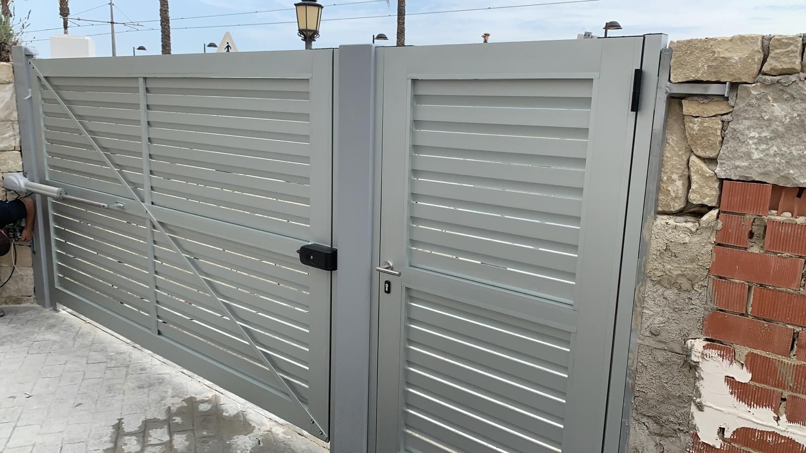 Una puerta gris está al lado de una pared de ladrillos.