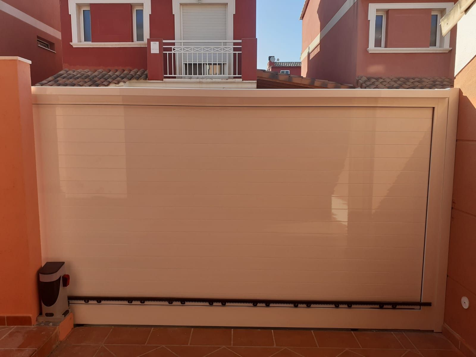 Una puerta corrediza blanca está abierta frente a un edificio rojo.