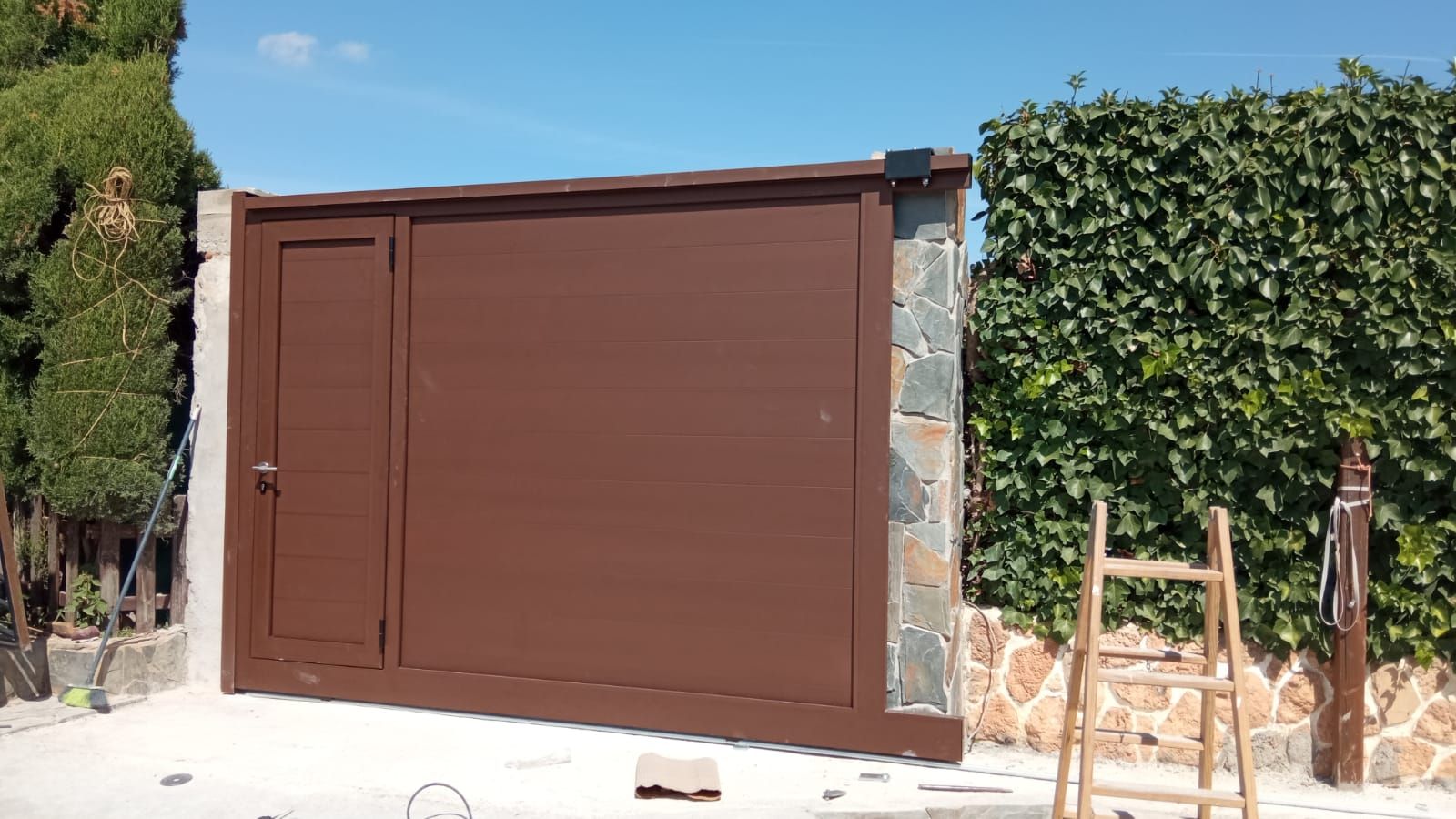 Se está construyendo una puerta marrón al lado de un muro de piedra.