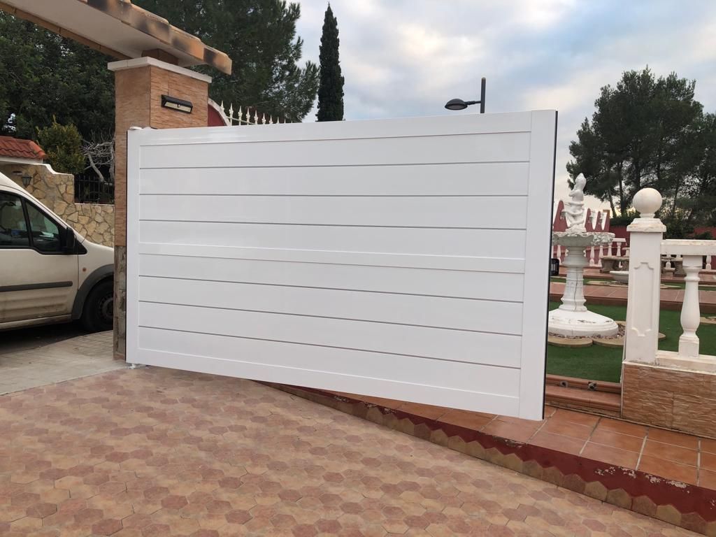 Un coche blanco está aparcado delante de una puerta blanca.