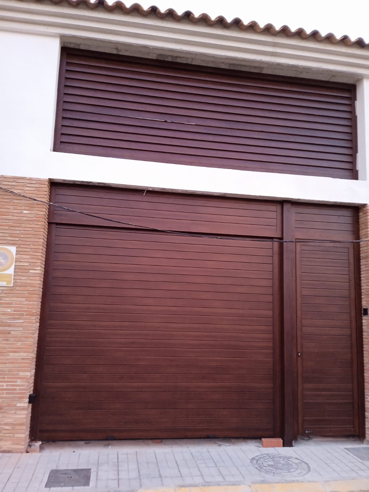 Una gran puerta de garaje marrón está en el costado de un edificio.