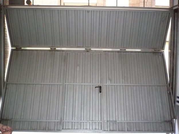 Una persona está parada frente a una puerta de garaje que está abierta.