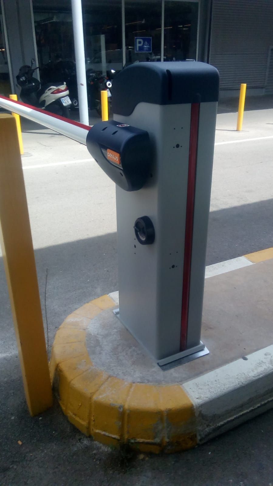 Hay una barrera de estacionamiento al costado de la carretera, al lado de un bordillo amarillo.
