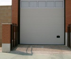 Una puerta de garaje blanca está abierta frente a un edificio de ladrillo.
