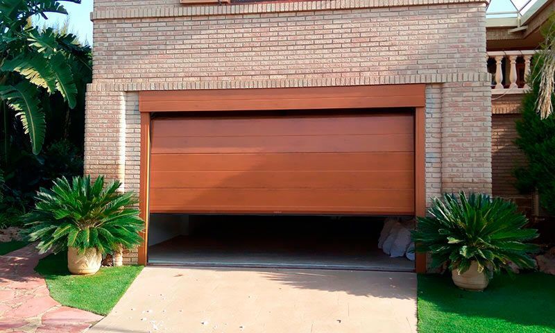 Una puerta de garaje de madera está abierta frente a una casa de ladrillo.