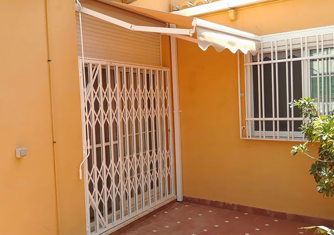 Un patio con reja y una ventana con toldo blanco.