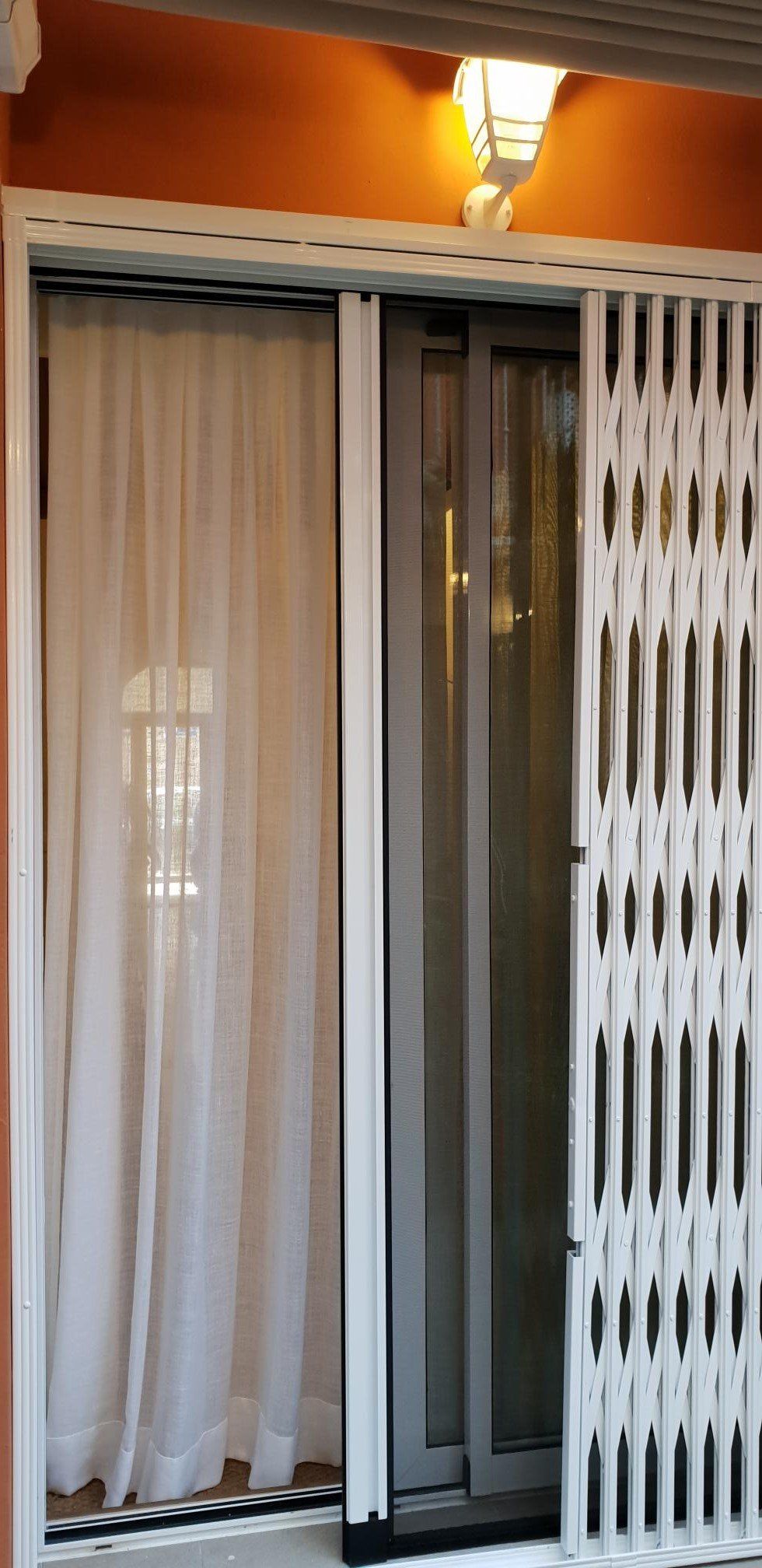 Una ventana con una cortina blanca y una puerta blanca.