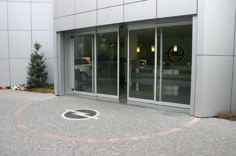 Un coche está aparcado delante de un edificio con puertas corredizas de cristal.