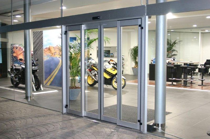 Una motocicleta está estacionada frente a una puerta de vidrio en una sala de exposición.