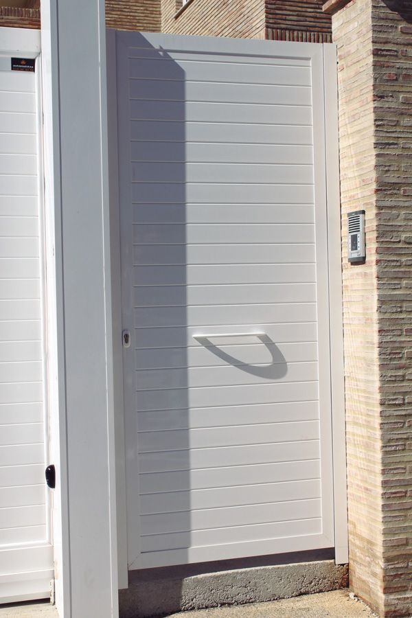 Una puerta blanca está al lado de una pared de ladrillos.