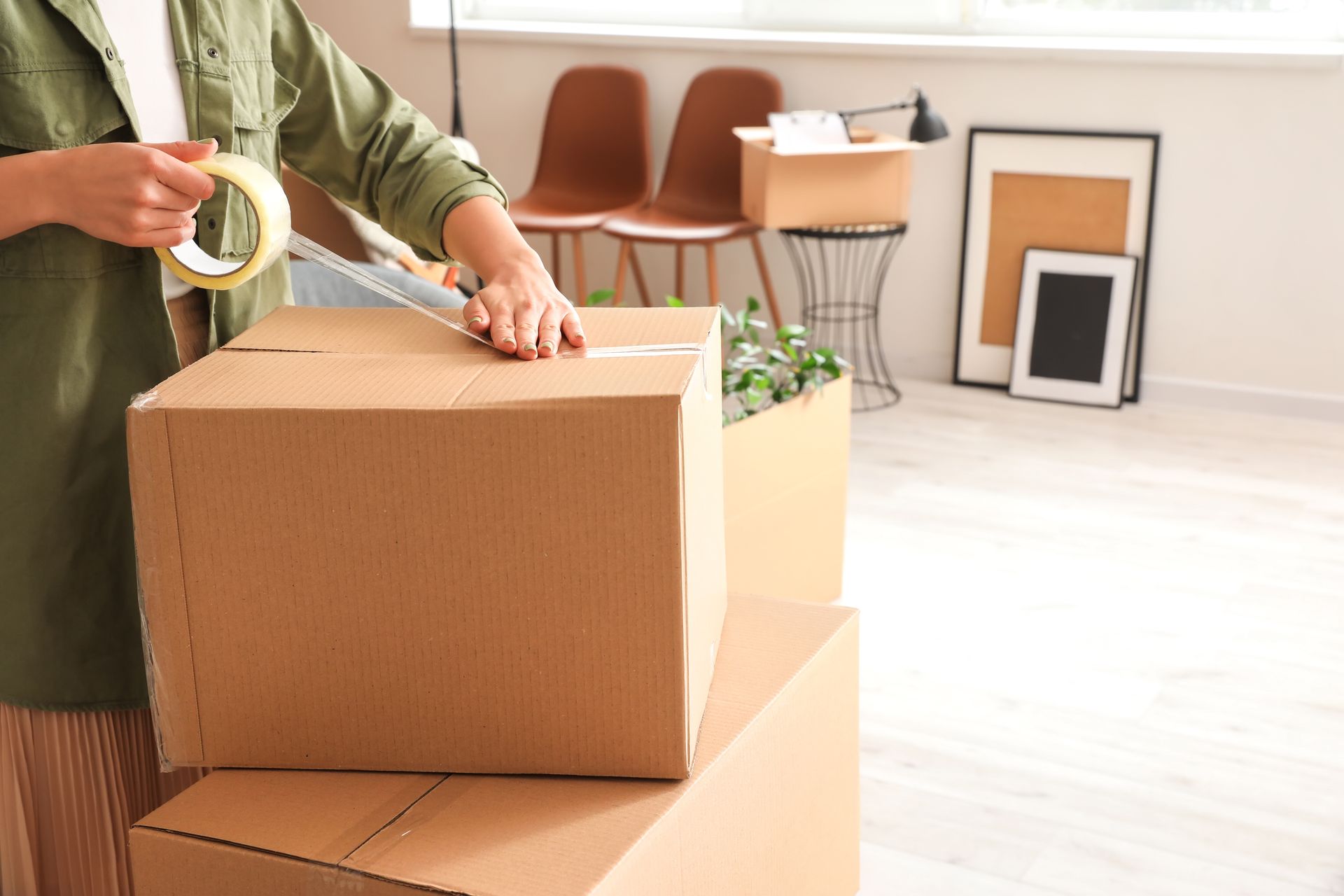 Une personne qui ferme un carton de déménagement