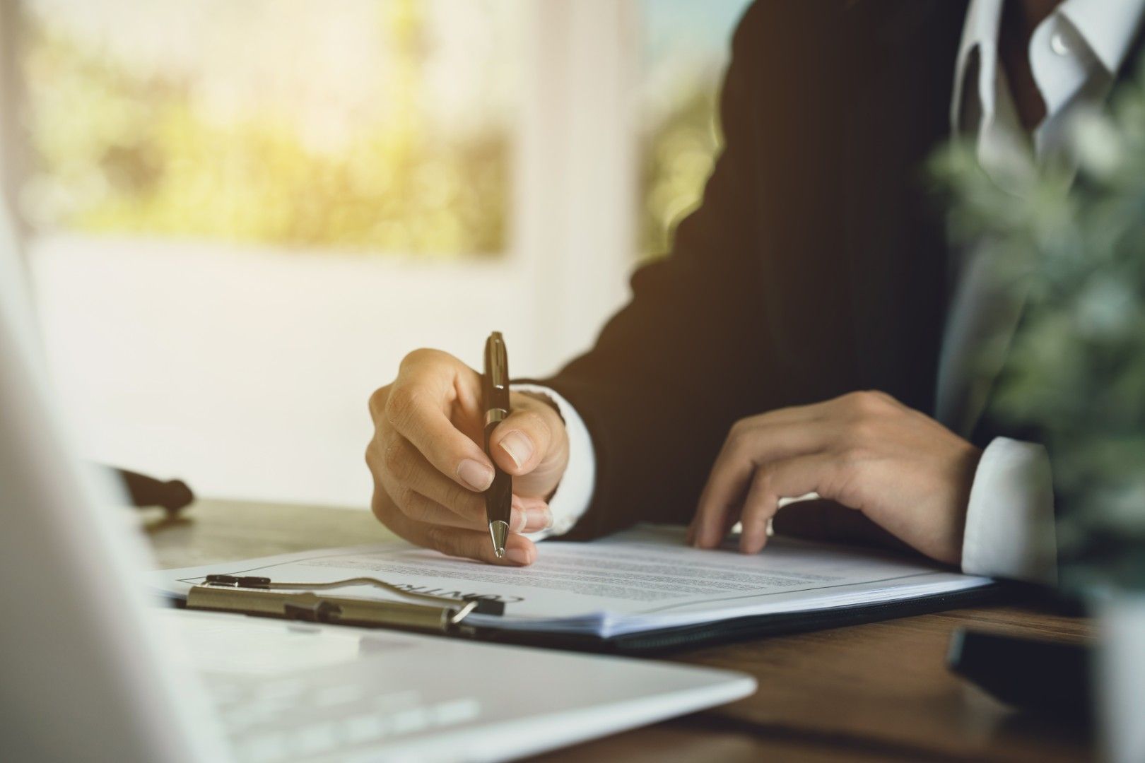 Prise de notes manuscrites sur un presse-papiers, à un bureau baigné d’une lumière chaleureuse