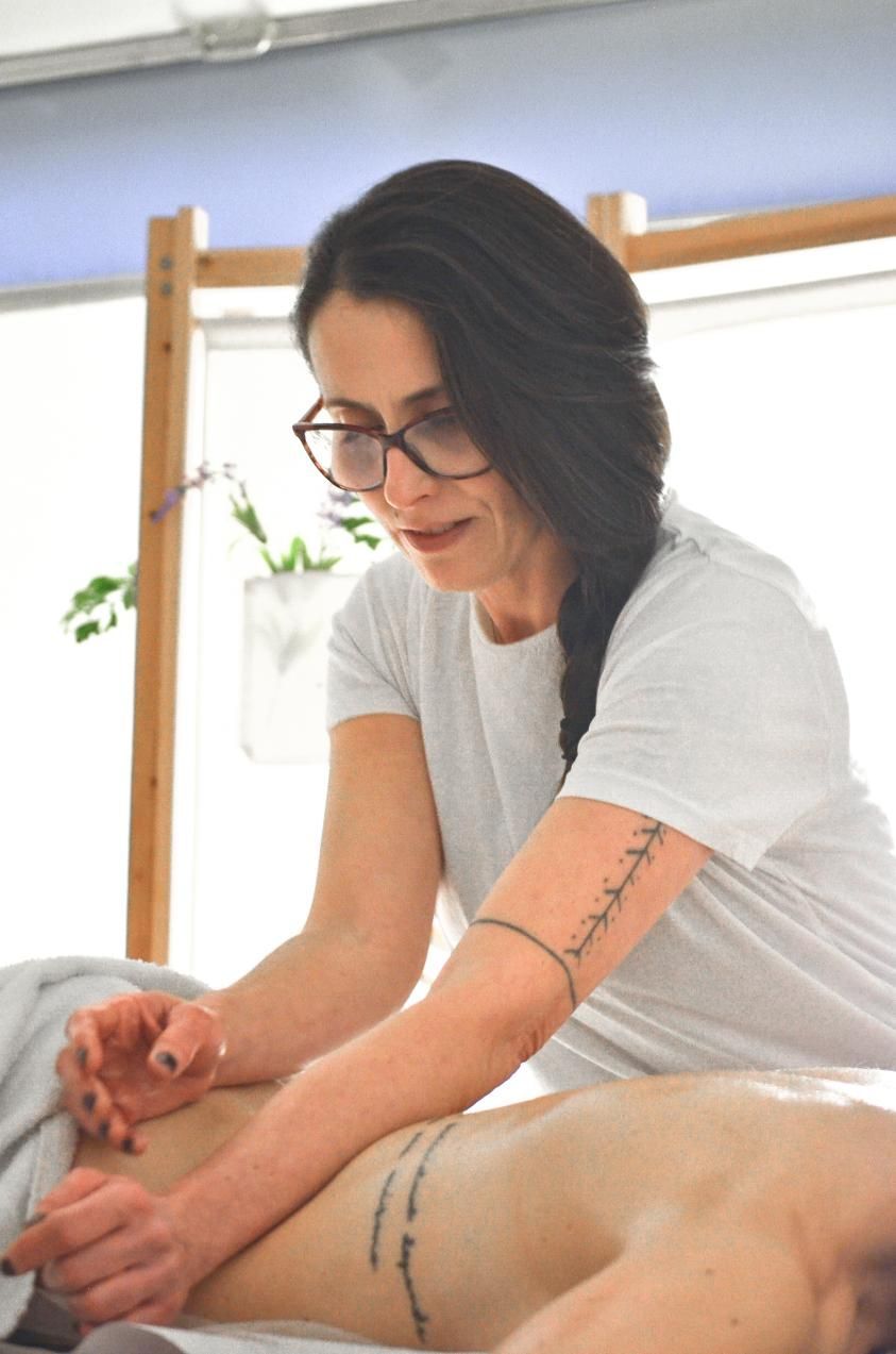 Cinco personas en un estudio de yoga, sentadas sobre colchonetas moradas, con los brazos detrás de la espalda.