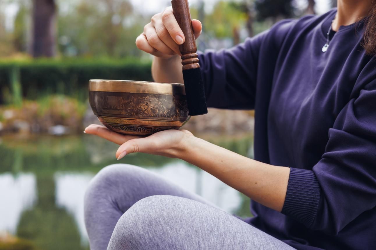 Cinco personas en un estudio de yoga, sentadas sobre colchonetas moradas, con los brazos detrás de la espalda.