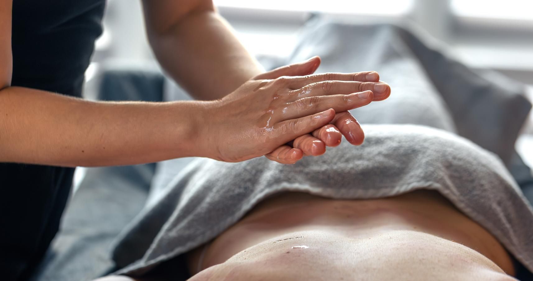 Cinco personas en un estudio de yoga, sentadas sobre colchonetas moradas, con los brazos detrás de la espalda.