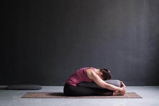 Cuatro personas vestidas con ropa deportiva practican yoga en un estudio, realizando la postura del triángulo.