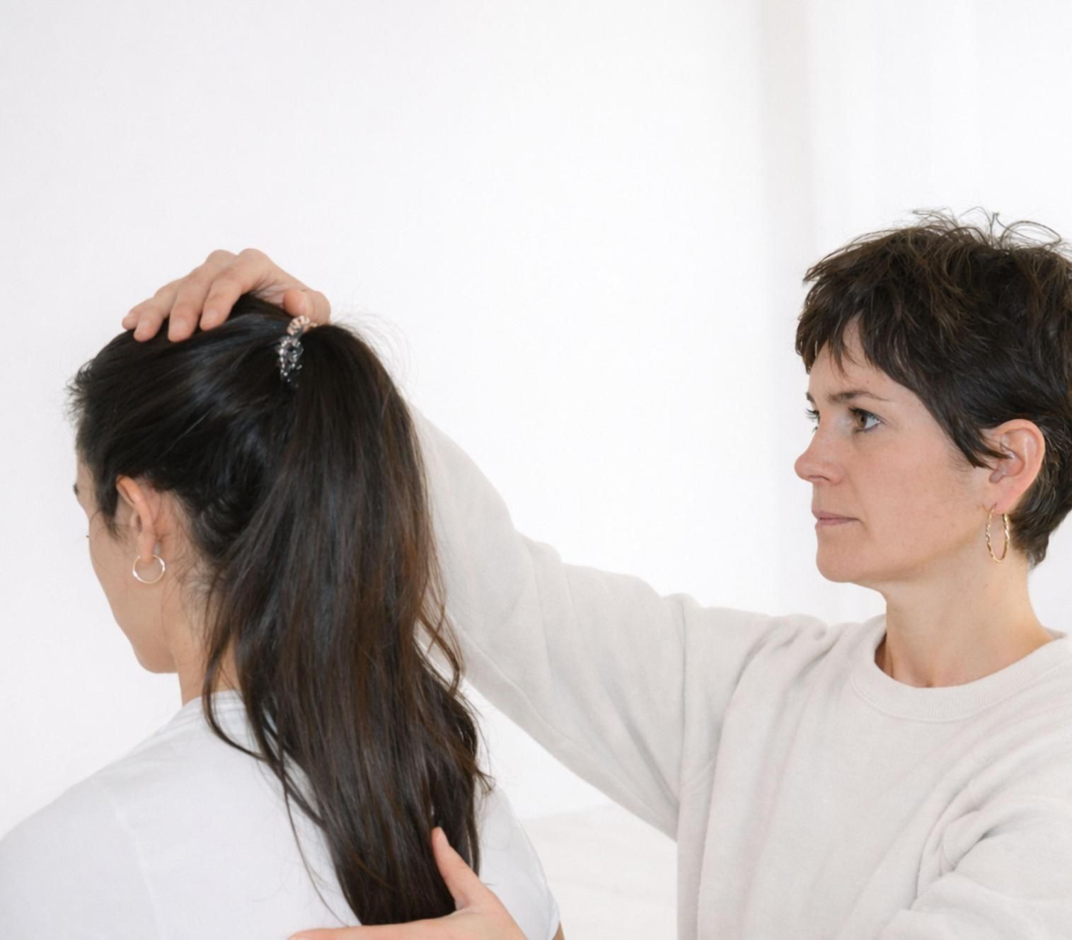 La mano de una mujer sobre la cabeza de otra, posiblemente ofreciéndole apoyo o examinándola.
