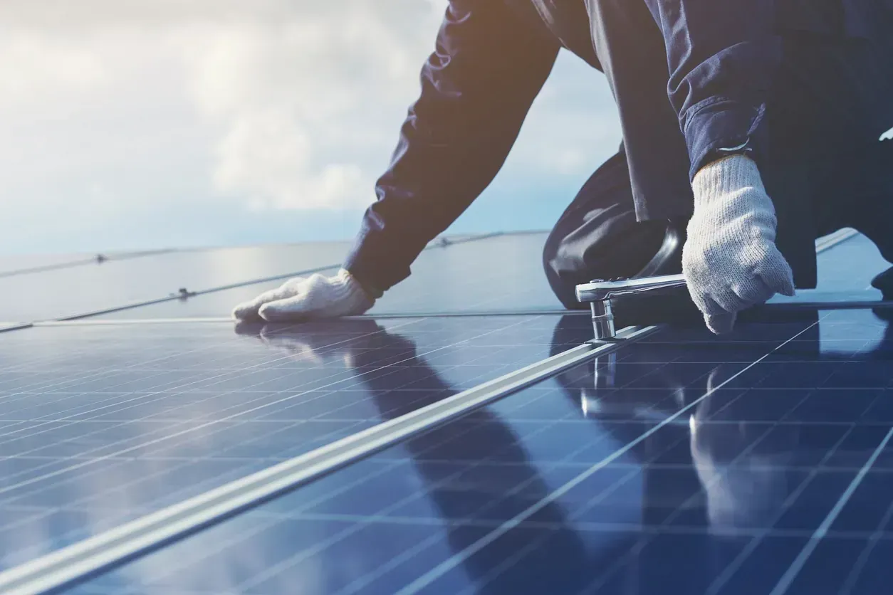 Un hombre está instalando paneles solares en un tejado.