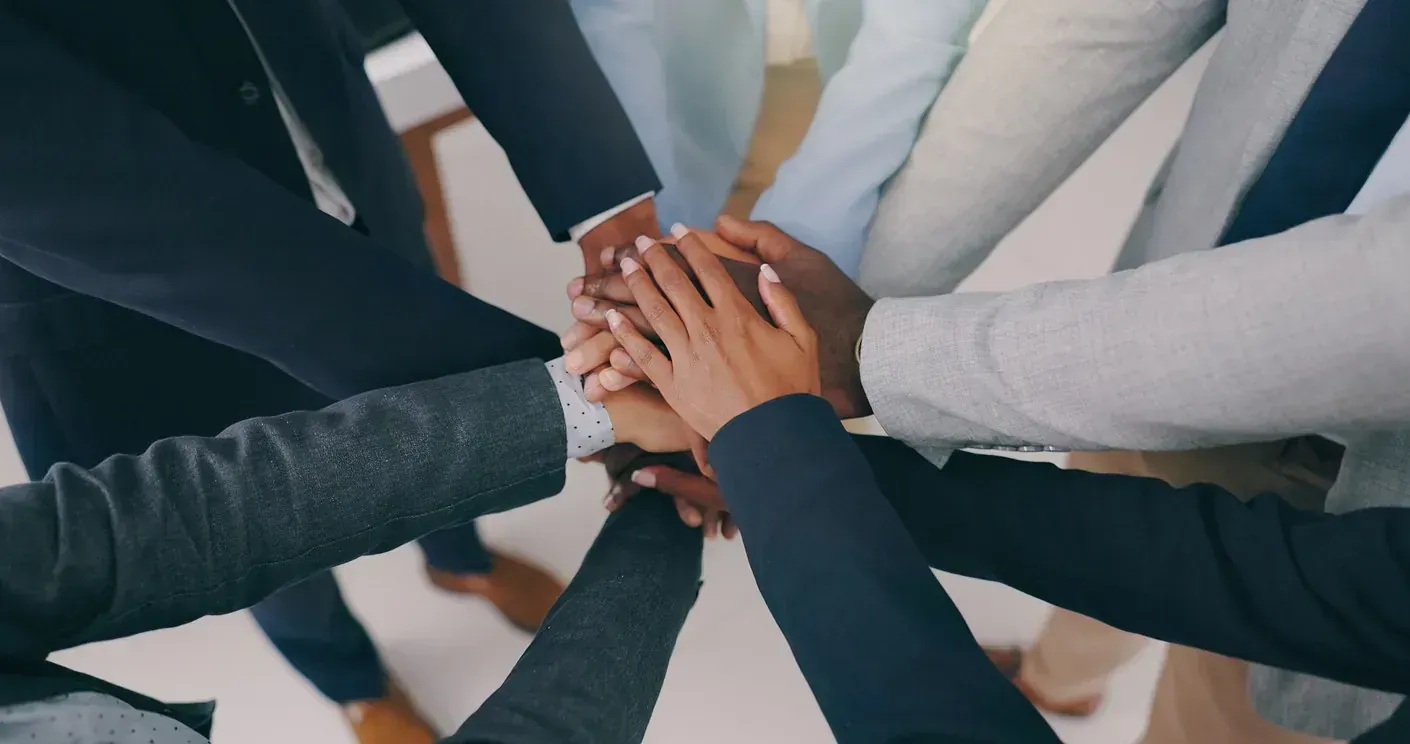 Un grupo de personas junta sus manos formando un círculo.
