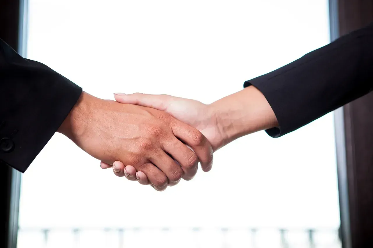 Un hombre y una mujer se dan la mano delante de una ventana.