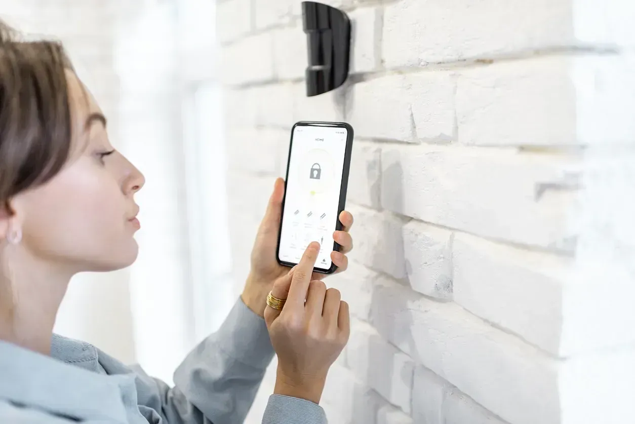 Una mujer está usando un teléfono inteligente para controlar un sistema de seguridad.