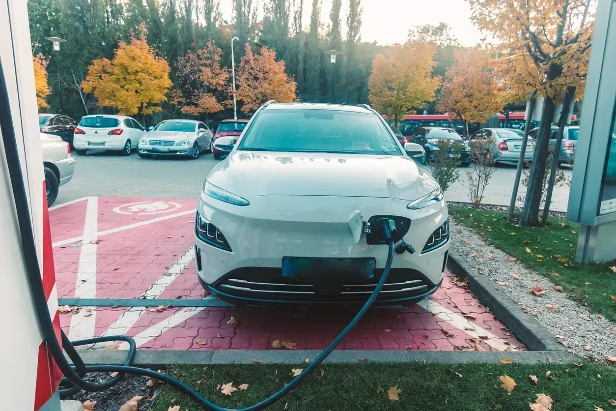 Un coche eléctrico blanco se está cargando en una estación de carga en un estacionamiento.