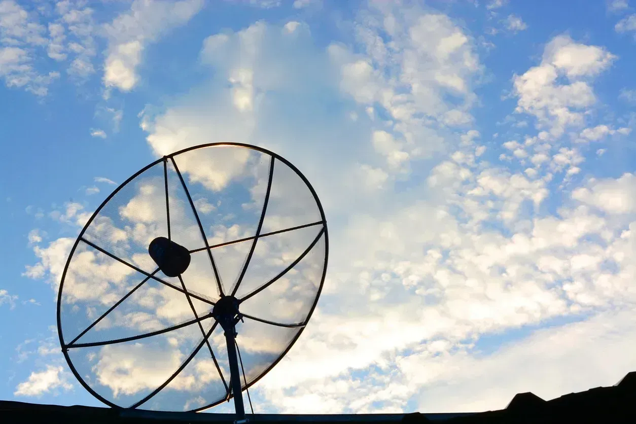 Una antena parabólica contra un cielo azul con nubes