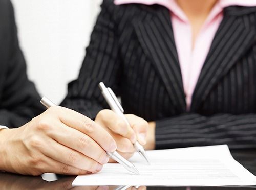 Un hombre y una mujer están escribiendo en un trozo de papel.