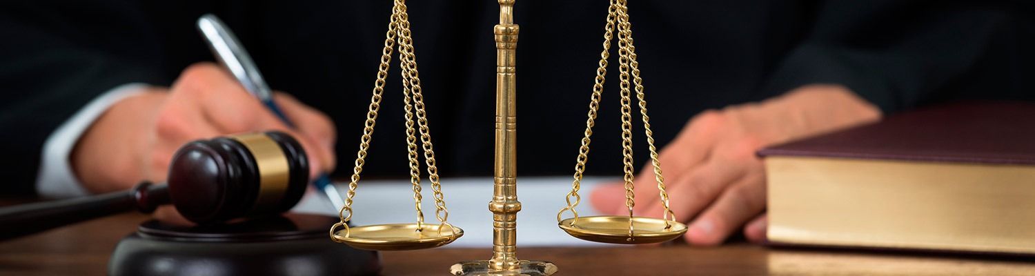 Un juez está sentado en una mesa con un mazo y una balanza de justicia.