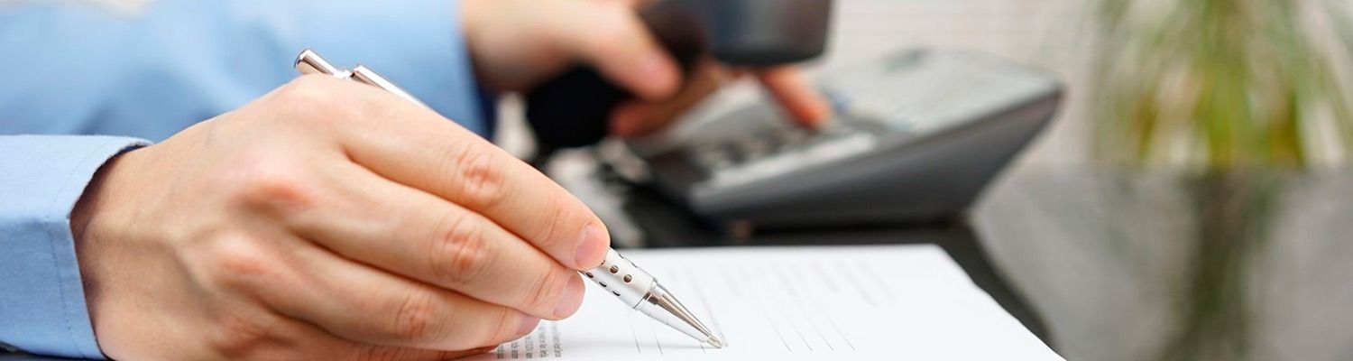 Un hombre está escribiendo en un trozo de papel mientras habla por teléfono.
