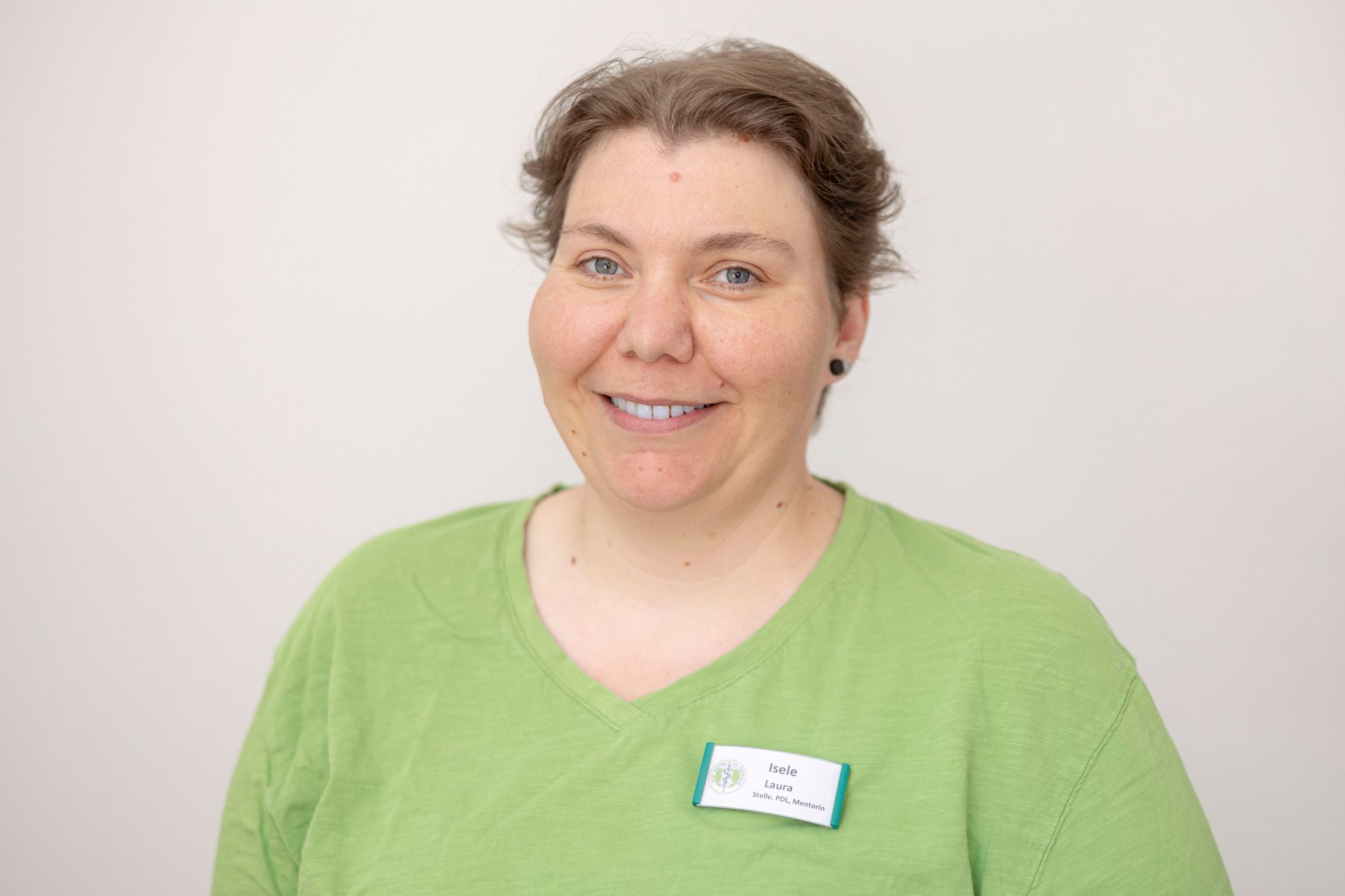 Eine Frau in einem grünen Hemd lächelt in die Kamera.