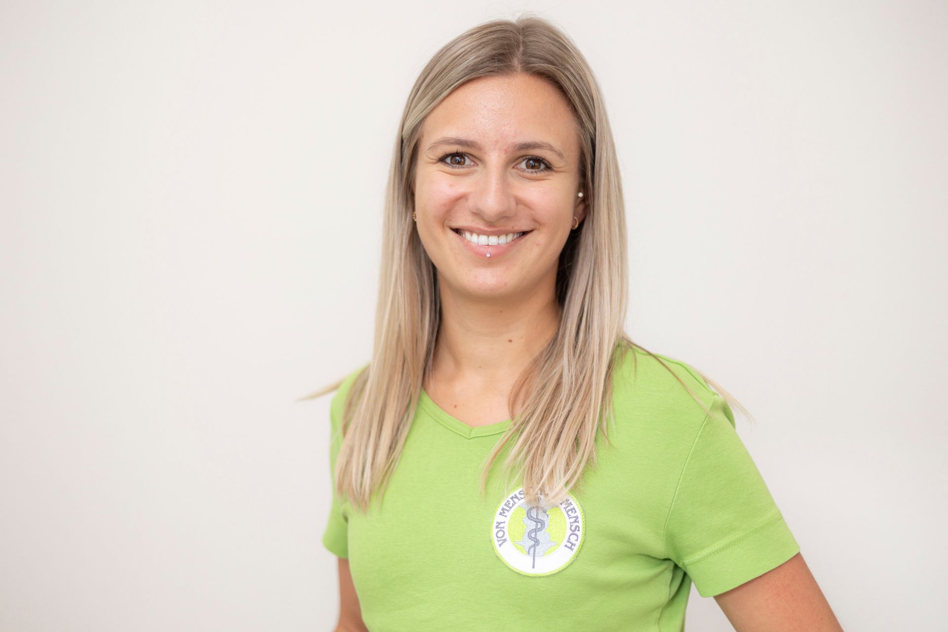 Eine Frau in einem grünen Hemd lächelt in die Kamera.