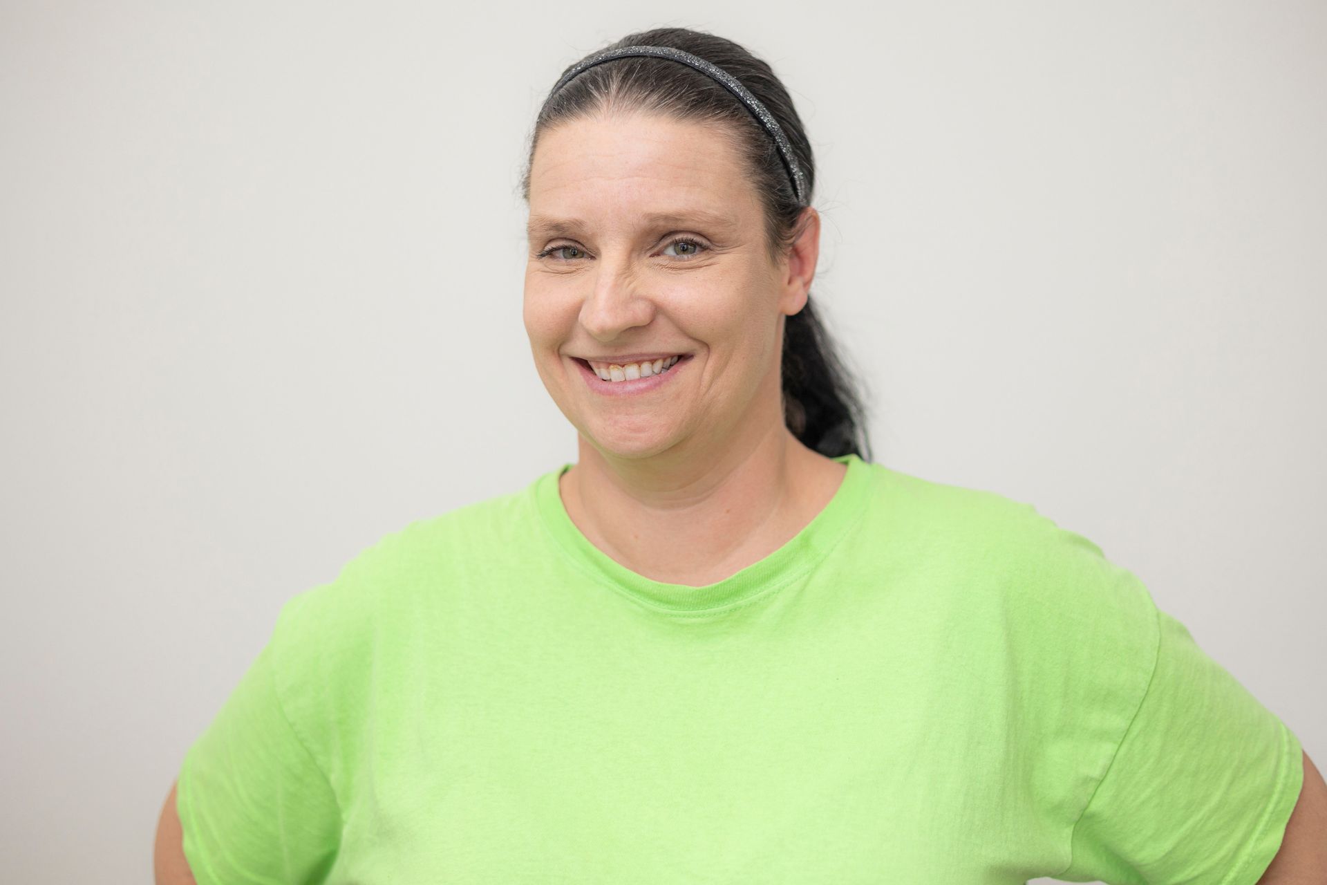 Eine Frau in einem grünen Hemd lächelt in die Kamera.
